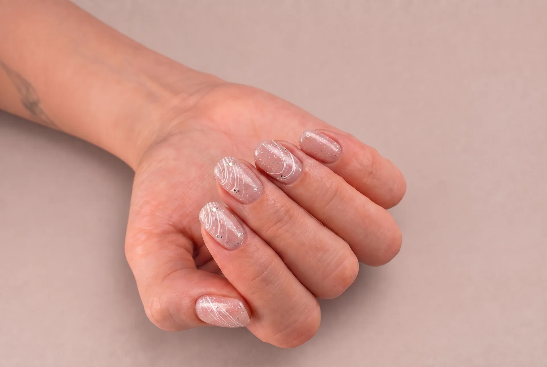 Manicura nude recién hecha, con líneas blancas finas y pedrería